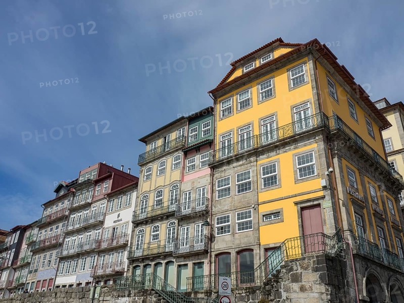 Facades of multi-storey colonial-style houses with yellow and white fronts under a blue sky, Colourful houses on a river with colourful boats and a large bridge, porto, Portugal, Europe