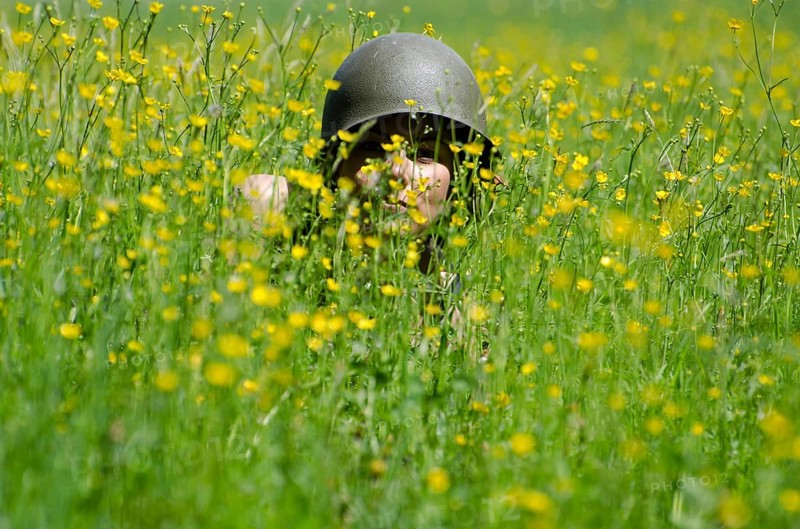 Scary Woman with Military Helmet Hidden in the Field with Yellow Flowers in a Sunny Day in Switzerland
