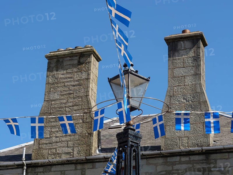 Stone houses in the village, decorated with blue and white flags and an old street lamp, grey houses with colourful flags in a seaside town, lerwick, Scotland, United Kingdom, Europe