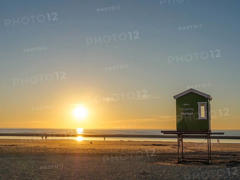 Sunset on the beach with a green wooden hut, peaceful sea and golden sky, evening mood on the beach with a sunset over the sea, beach chairs in the sunset, lnageoog, germany