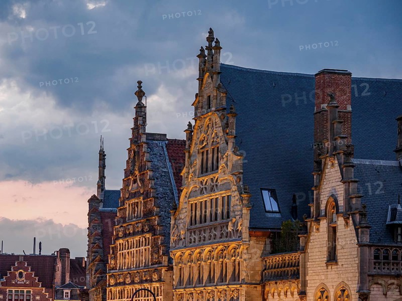 Ornate historic buildings with gabled roofs in Bruges in the light of dusk, historic buildings with towers and bridges on a river at dusk, gent, belgium