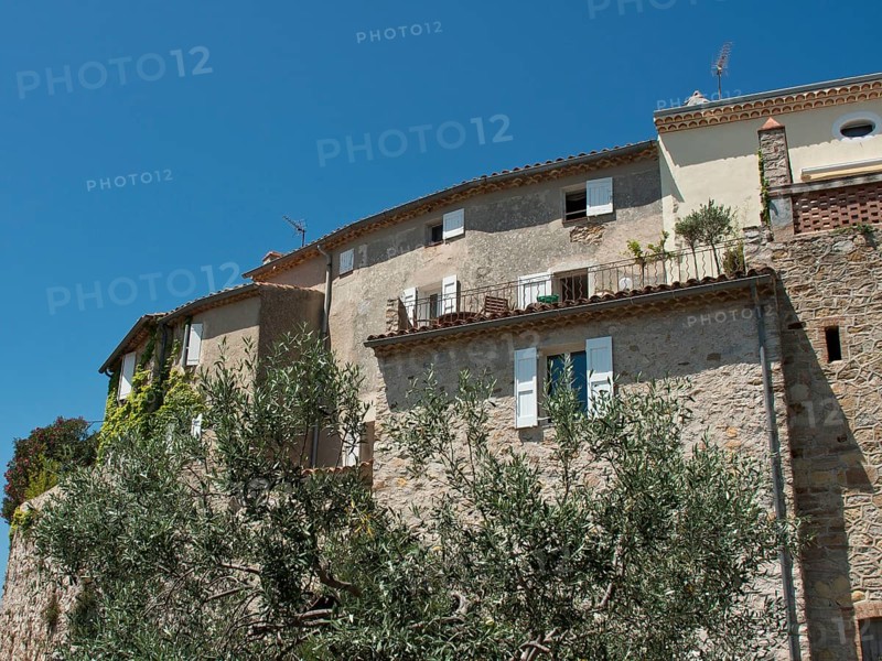 Rustic stone houses with white shutters and vegetation against a clear blue sky, Provence, le Castellet, France, Europe