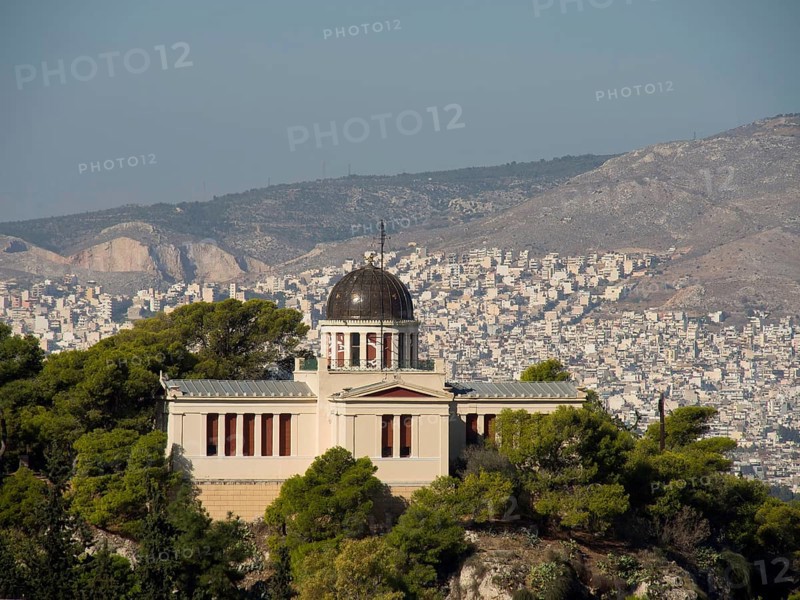 Historic building with a dome on a hill surrounded by trees and a cityscape, Ancient building with columns and trees on the Acropolis in Athens against a blue sky, athens, greece