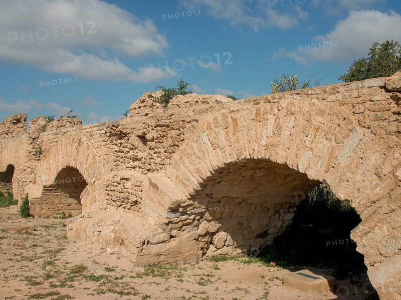 Massive, ancient stone arches of a city wall under a clear blue sky bear witness to past history, Tunis in Africa with ruins from Roman times, modern mosques and blue and white houses in sidi-bou-said, Tunis, Tunisia, Africa