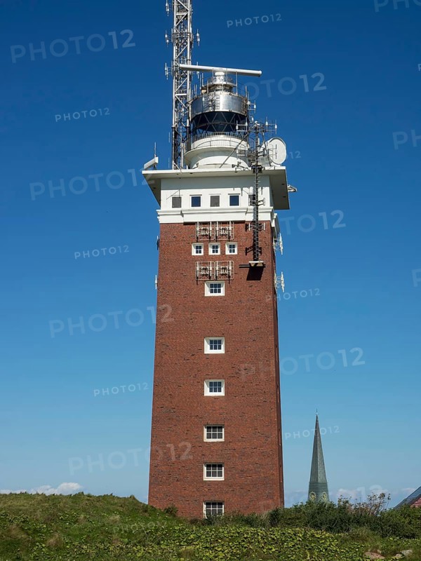 High brick lighthouse under blue sky with technical superstructures, Heligoland, Germany, Europe