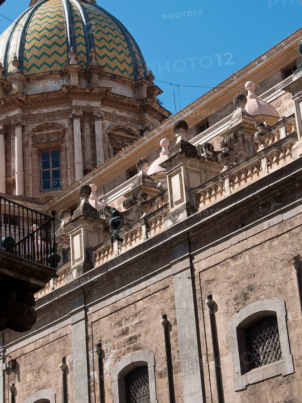 Historic church with a beautiful dome and detailed decorations on its facade, palermo in sicily with an impressive cathedral, monuments and old houses with balconies, palm trees and flowers in italy, palermo, sicily