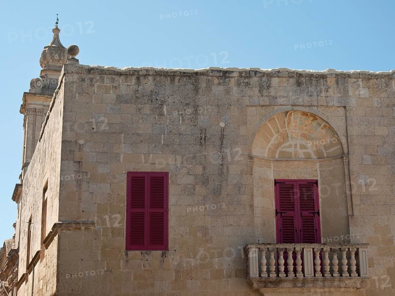 An old building with red shutters and a small balcony under a clear sky, the town of mdina on the island of malta with historic houses, colourful balconies, magnificent churches, mdina, Malta, Europe