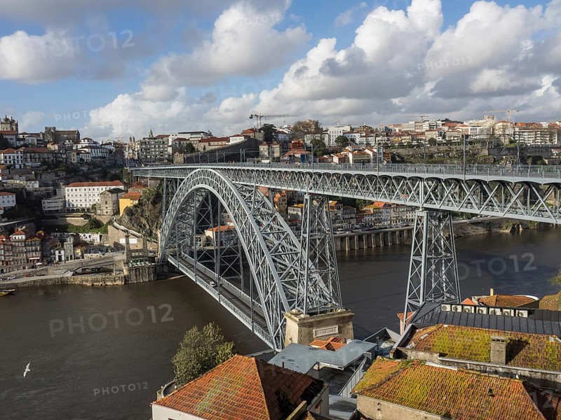 Steel bridge over a river in a historic city in sunny weather with clouds, spring in the old town of Porto on the Douro with historic houses, Porto, portugal