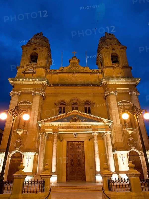 Illuminated church facade at night, with two towers, lamps and decorative elements, Valetta, Malta, Europe