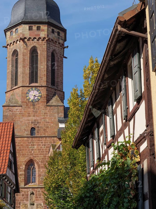 Stone church tower and half-timbered houses with autumn leaves under a blue sky, historic half-timbered houses in the Palatinate, kandel, Germany, Europe