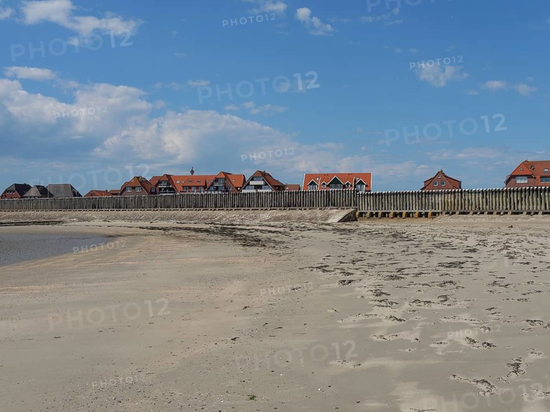 Empty beach with traces in the sand and traditional buildings in the background, Baltrum Germany