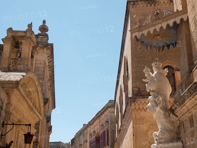 A street of historic buildings and statues under a blue sky, the town of mdina on the island of malta with historic houses, colourful balconies, magnificent churches, mdina, Malta, Europe