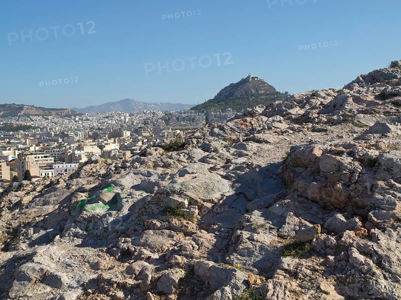 Stony landscape with a view of the city and surrounding hills, Ancient buildings with columns and trees on the Acropolis in Athens against a blue sky, athens, greece