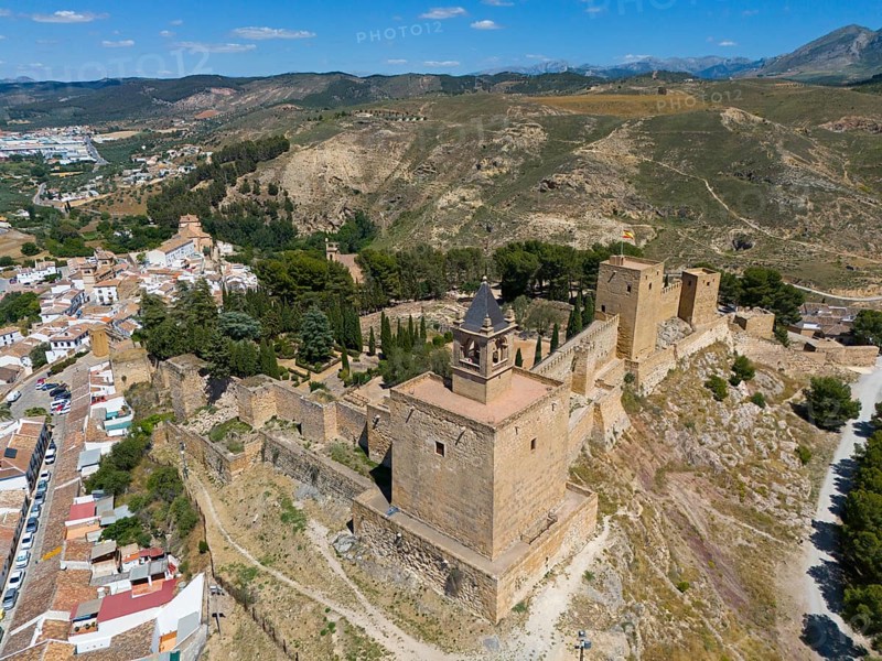 Historic castle complex on a hill in a mountainous area of Spain, surrounded by vegetation in sunny weather, aerial view, fortress hill, Alcazaba, Antequera, Malaga, Andalusia, Spain, Europe