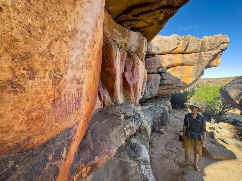 Young man looking at prehistoric depiction of woman on a rock, San rock paintings, Sevilla Art Rock Trail, Cederberg Mountains, near Clanwilliam, Western Cape, South Africa, Africa