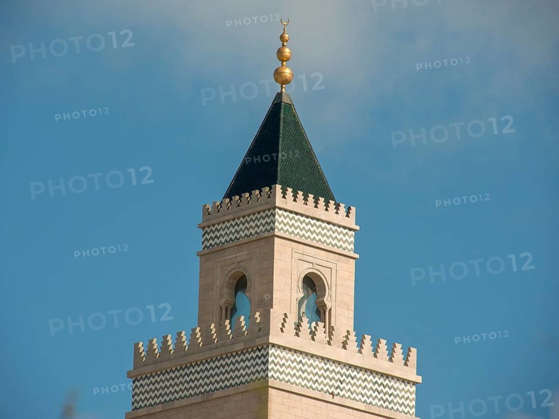 A tall minaret with a green spire and golden decorations rises into the sky, Tunis in Africa with ruins from Roman times, modern mosques and blue and white houses in sidi-bou-said, Tunis, Tunisia, Africa