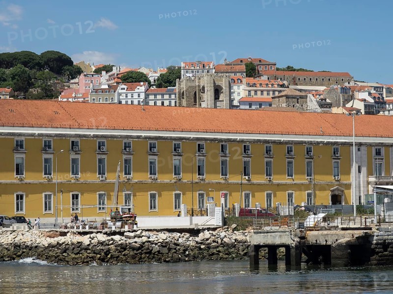 Coastal town with yellow buildings and a jetty by the water, surrounded by hills and houses, Lisbon, Portugal, Europe