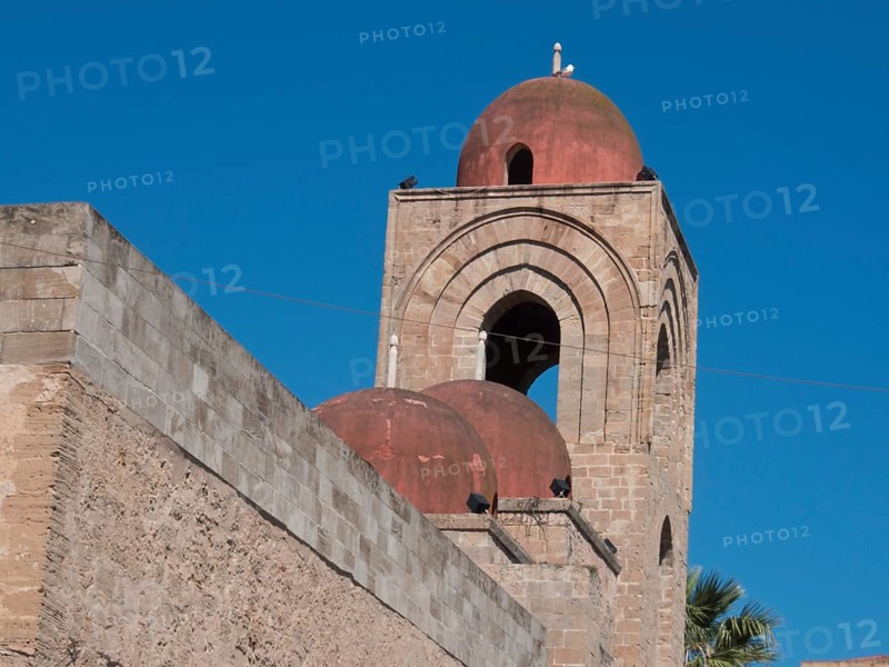 Historic church with red domes and towers against a clear blue sky, palermo in sicily with an impressive cathedral, monuments and old houses with balconies, palm trees and flowers in italy, palermo, sicily