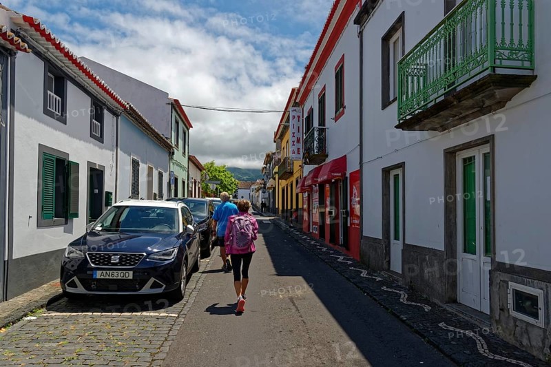 Street with parked cars and people walking under a sunny sky with scattered clouds, coastal town of Ribeira Grande, Santa Barbara, Sao Miguel, Azores, Portugal, Europe