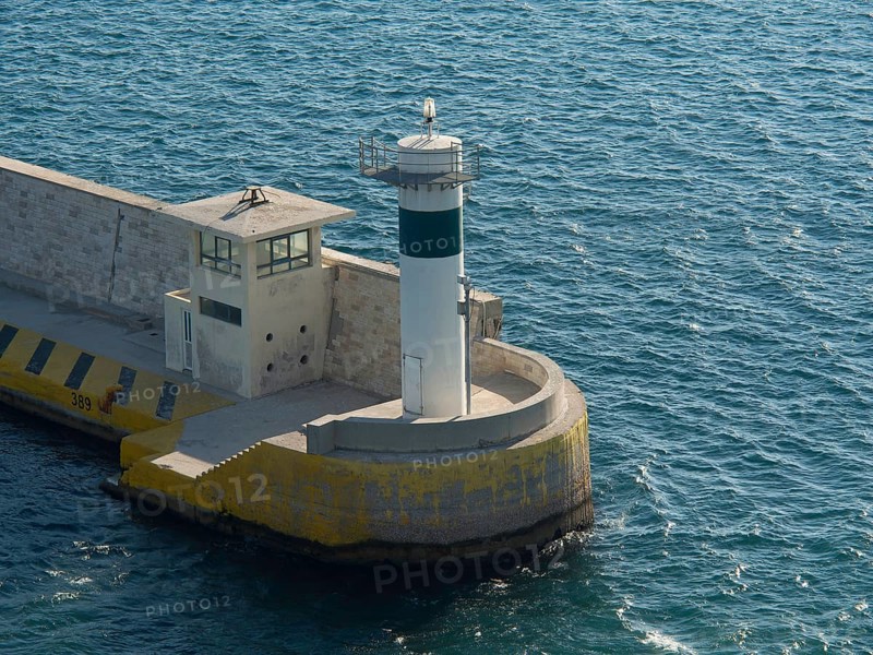 A lighthouse at a harbour surrounded by blue water in daylight, Ancient buildings with columns and trees on the Acropolis in Athens against a blue sky, athens, greece
