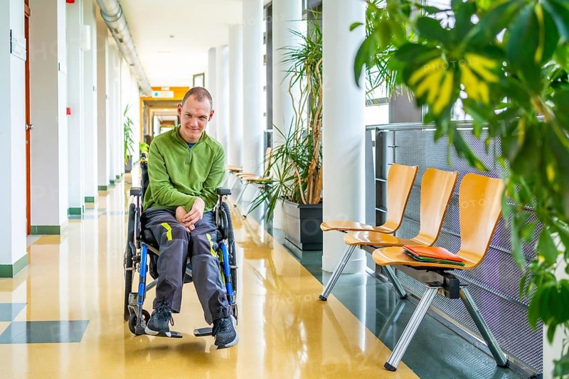 Full length portrait of a caucasian adult man with cerebral palsy sitting in an electrical wheelchair in the university
