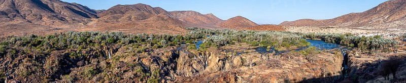 Panorama, Kunene River with green vegetation in dry red mountain landscape, waterfall and African Baobab (Adansonia digitata), in the evening light, Epupa Falls, Kunene, Namibia, Africa