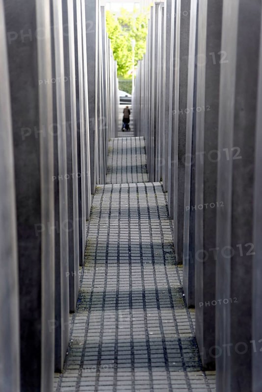 Holocaust memorial in Berlin, Germany Holocaust memorial in Berlin, Germany, Europe, Narrow path between concrete walls with light and green area in the background, Europe