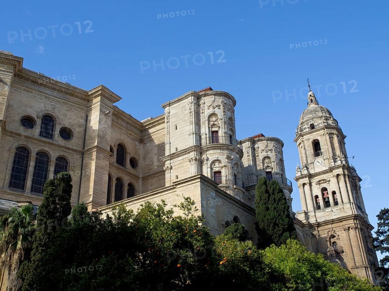 Large cathedral with impressive stone towers and detailed facades under a blue sky, The city of Malaga on the Mediterranean with the historic fortress and palm trees, Malaga, spain