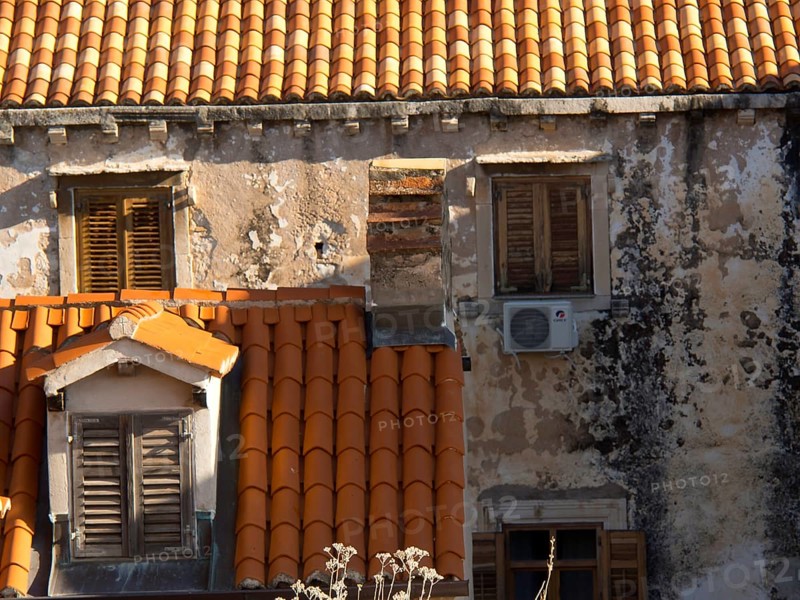 Old buildings with red tiled roofs and closed shutters, partially dilapidated facades, the old town of Dubrovnik with historic houses, churches, red roofs and fortress walls, dubrovnik, coratia