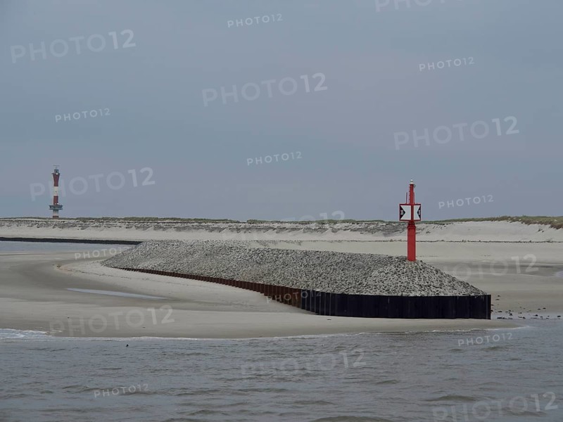 Red beacon on a gravel embankment along the coast with sand dunes and grey sky, buhne on an island in the north sea with tower and sea mark, Wangerooge, Germany, Europe