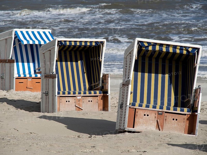Three beach chairs in blue and white design on the beach in front of the sea, beach chairs on the sandy beach with North Sea waves in the background, wangerooge, Germany, Europe