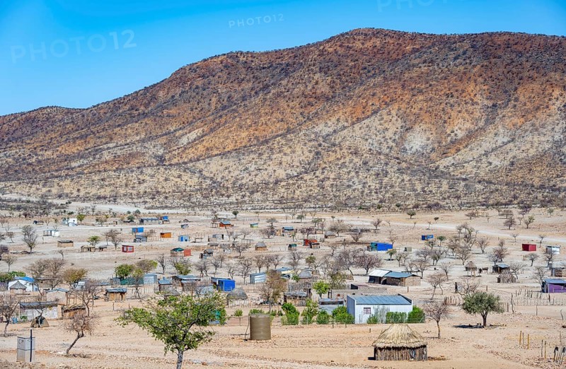Houses in the village of Epupa, barren dry landscape with white and yellow hills, Kaokoveld, Kunene, Namibia, Africa