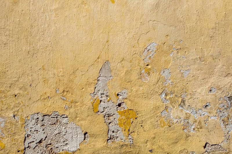 A weathered yellow wall with peeling paint and visible damage, Rhodes, Greece, Europe