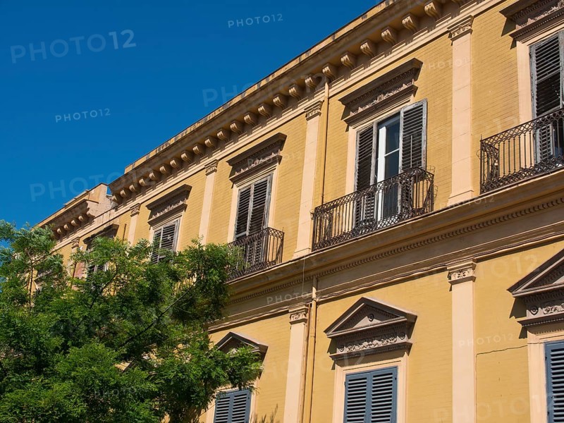 Historic building with wrought iron balconies and shutters on a sunny day, palermo in sicily with an impressive cathedral, monuments and old houses with balconies, palm trees and flowers in italy, palermo, sicily