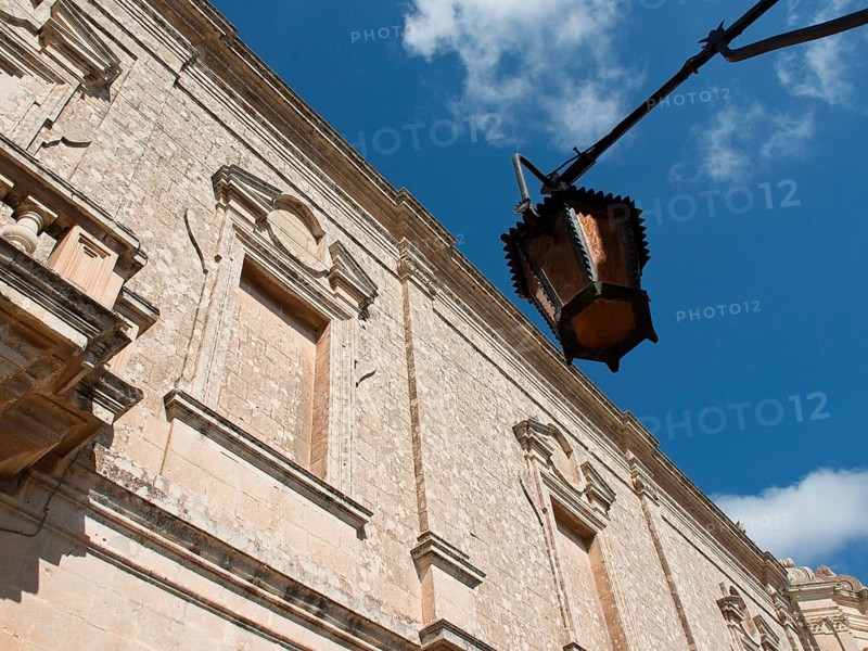 View of historic stone wall with street lamp against a blue sky, the town of mdina on the island of malta with historic houses, colourful balconies, magnificent churches, mdina, Malta, Europe