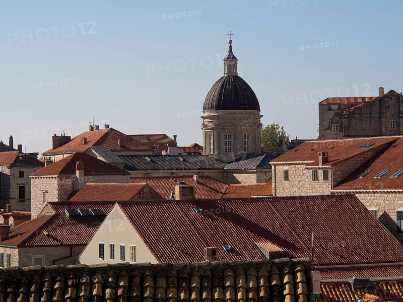 Historic buildings and a church with a dome surrounded by red tiled roofs under a clear blue sky, the old town of Dubrovnik with historic houses, churches, red roofs and fortress walls, dubrovnik, coratia