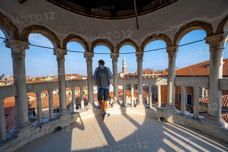 Young man looking over Venice with campanile, tower of Palazzo Contarini del Bovolo, palace with spiral staircase, Venice, Veneto, Italy, Europe