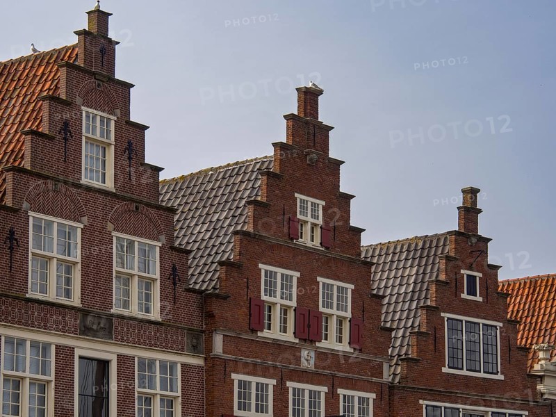 Historic gabled brick houses arranged in rows, with pointed roofs and windows in a traditional European architectural style, historic houses in Hoorn and ships in the harbour, hoorn, the netherlands