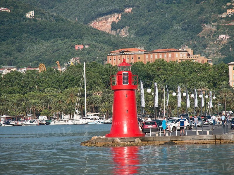 A red lighthouse at the harbour with boats, surrounded by trees and mountains in the background, Bari, Italy, Europe