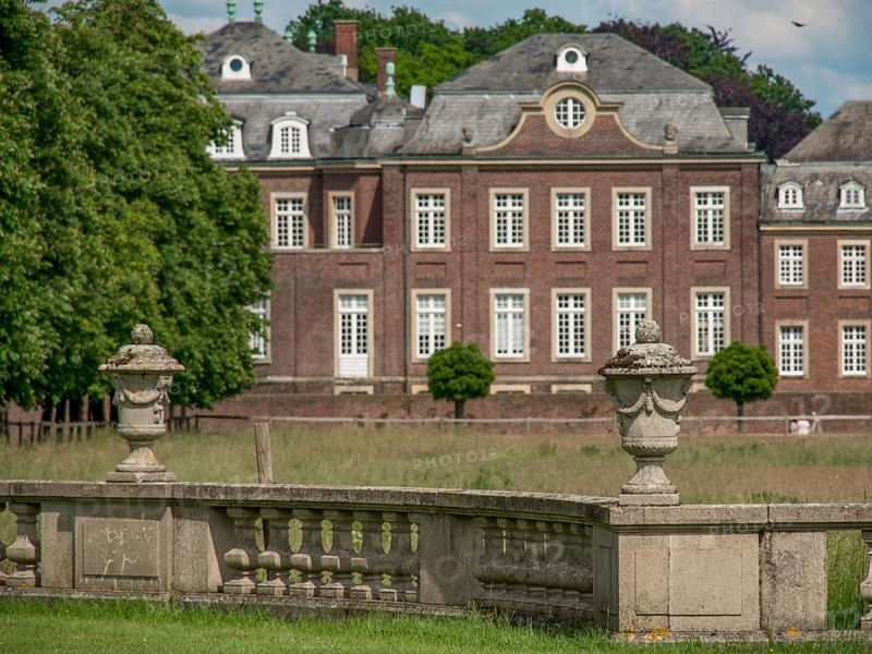 Stone vases in a green park, with a historic castle in the background, historic castle with a green park with sculptures and paths, nordkirchen, germany