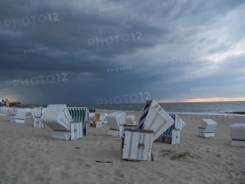 Abandoned beach chairs on the beach under a dramatic cloudy sky, the north sea island baltrum with grassy dune, colourful beach chairs on the beach and clouds over the sea, Baltrum Germany