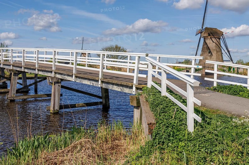 White bridge over a canal, windmill in the background, calm nature-related atmosphere, windmills of Kinderdijk on a river, Kinderdijk, Netherlands