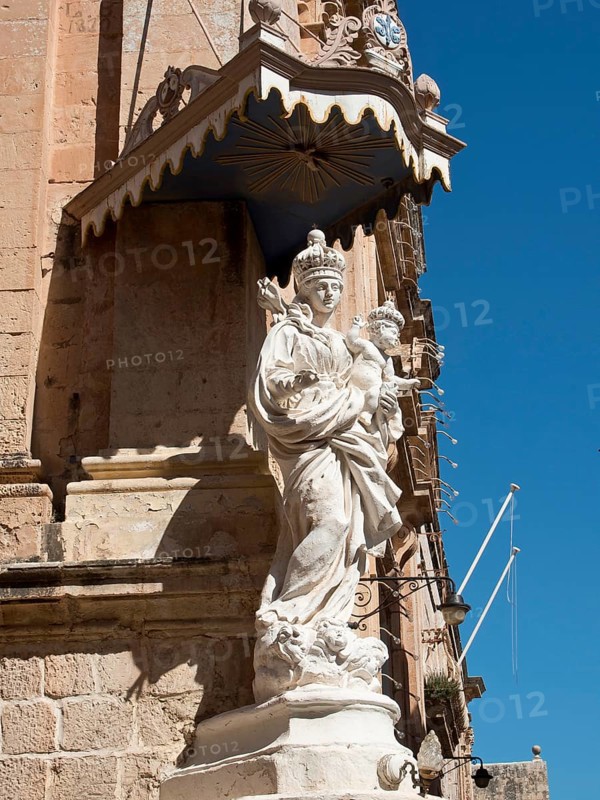 A stone statue of the holy mother and child in front of a historic stone facade, the town of mdina on the island of malta with historic houses, colourful balconies, magnificent churches, mdina, Malta, Europe