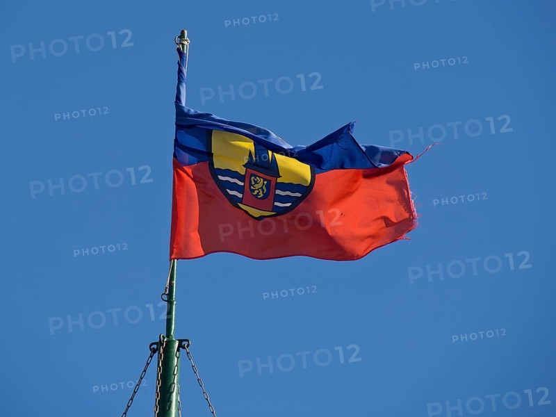 A flag with a coat of arms fluttering vividly in the wind against a clear blue sky, Borkum, Germany, Europe