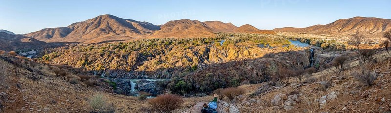 Panorama, Kunene River with green vegetation in dry red mountain landscape, waterfall and African Baobab (Adansonia digitata), in the evening light, Epupa Falls, Kunene, Namibia, Africa