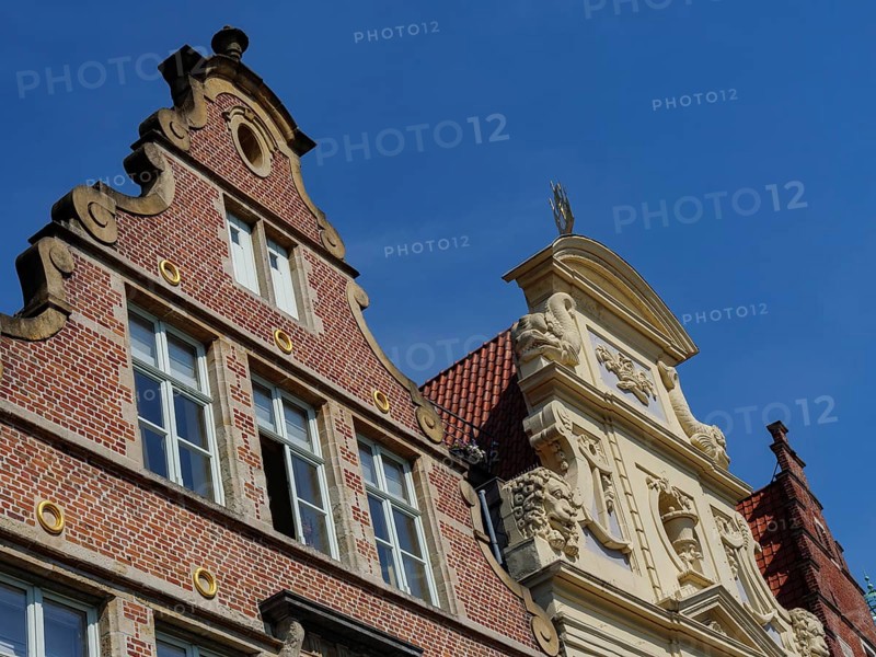 Historic brick building with decorative ornaments under a clear blue sky, medieval facades with historic churches and buildings in a riverside town, Ghent, Belgium, Europe