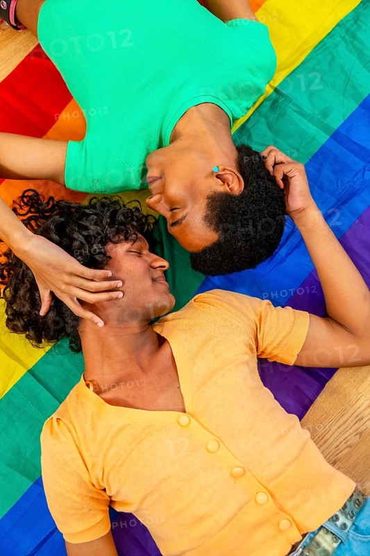 Vertical top view photo of a male latin gay couple caressing over a LGBT rainbow flag
