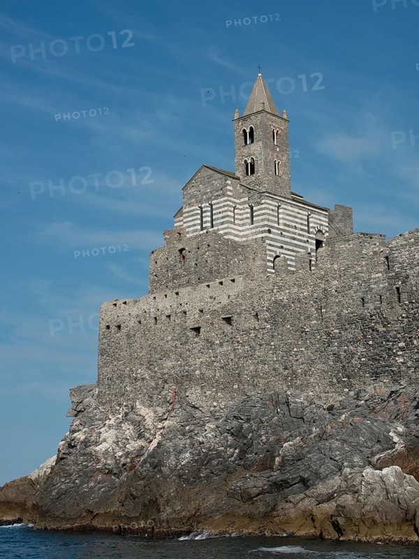 A historic stone church perched on rocky cliffs on the coast against a clear sky, Bari, Italy, Europe
