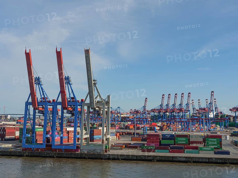 An industrial harbour terminal with lots of containers, cranes and storage areas on a sunny day, a beautiful city on the river with harbour, shipyards, houses and ships, Hamburg, Germany, Europe
