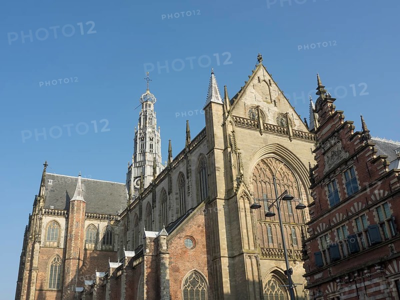 View of a Gothic church and neighbouring historic buildings under a clear sky, Haarlem, Netherlands